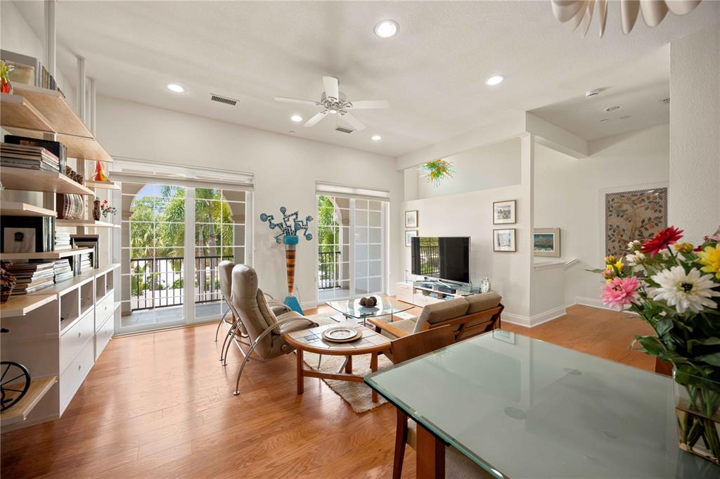 An open-concept living room and kitchen featuring hardwood floors, a ceiling fan, and shelving — 435 NOKOMIS AVENUE S UNIT 312, VENICE, FL