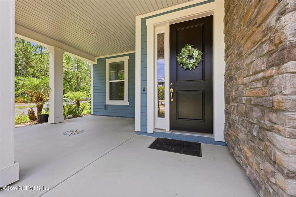 A covered front porch features a black door, stone siding, and a concrete floor — 13 VERDURE STREET, ST JOHNS, FL
