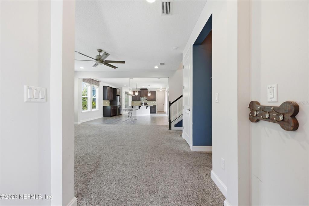 A carpeted entryway leads to an open-concept kitchen with dark cabinetry and a ceiling fan — 13 VERDURE STREET, ST JOHNS, FL