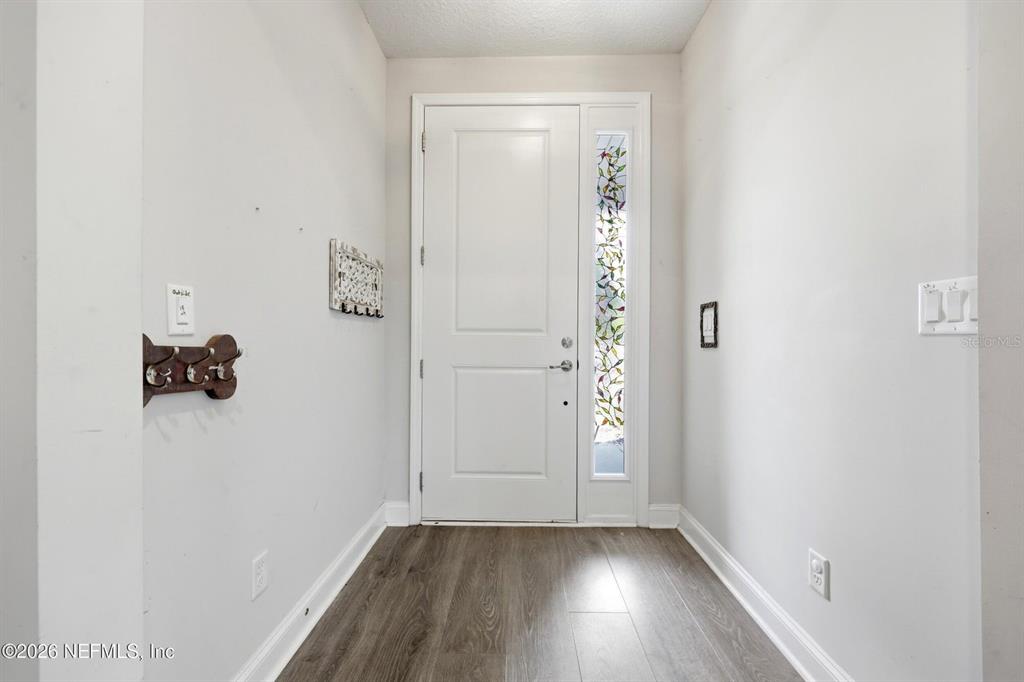 An entryway features a white front door with a stained glass sidelight and wood-look flooring — 13 VERDURE STREET, ST JOHNS, FL
