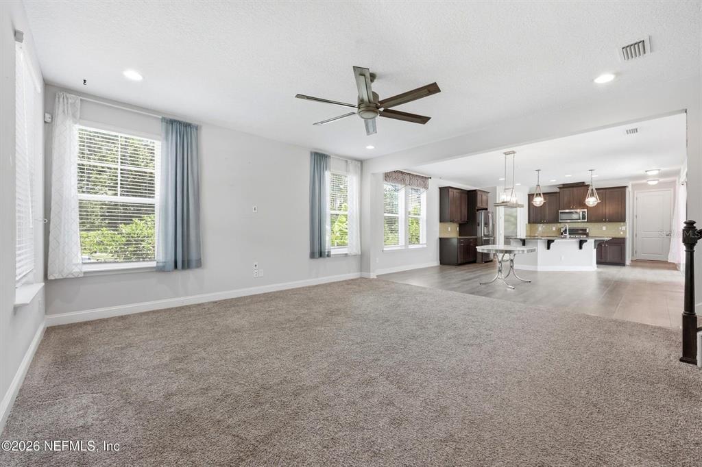 A carpeted living room opens into a kitchen with dark cabinets and a breakfast bar — 13 VERDURE STREET, ST JOHNS, FL