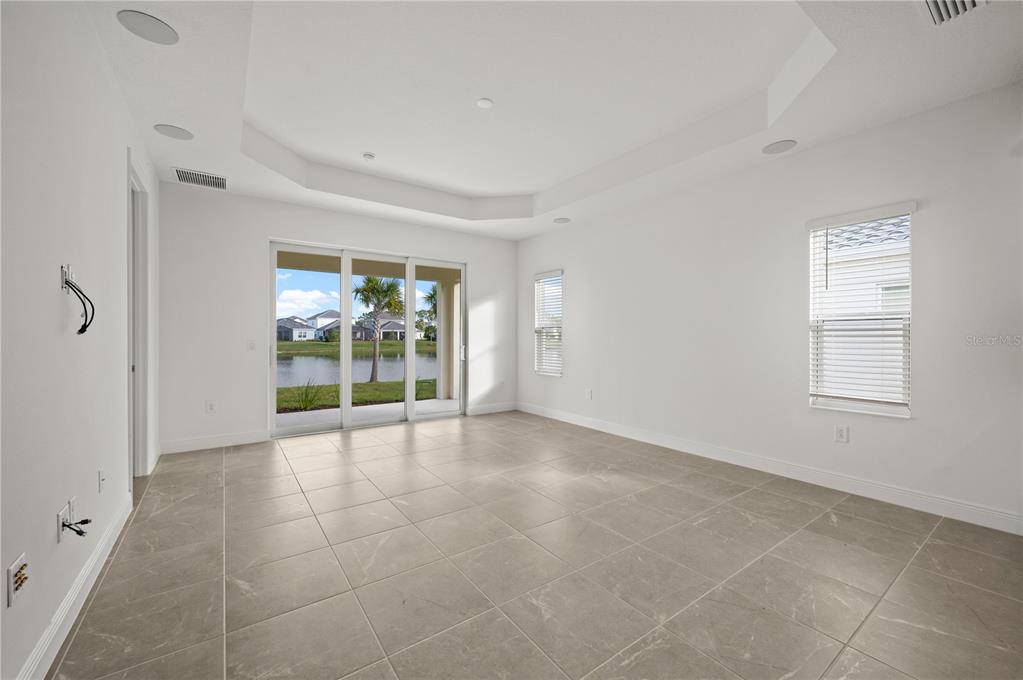 A modern kitchen features white cabinetry, quartz countertops, a center island, and stainless steel appliances — 10366 LAKE GEORGE AVENUE, SARASOTA, FL