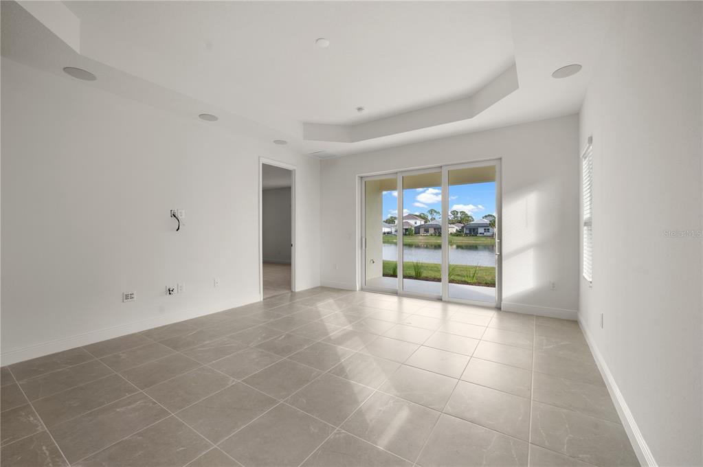 A modern kitchen features white cabinetry, a central island with a sink, and light-colored countertops — 10366 LAKE GEORGE AVENUE, SARASOTA, FL