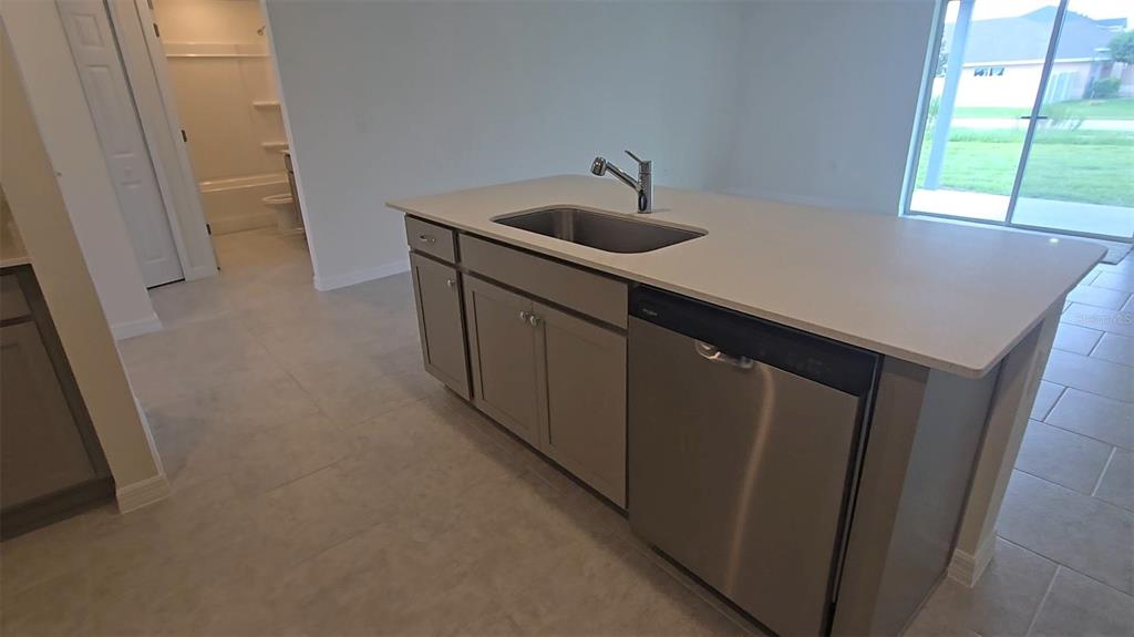 A kitchen island with a stainless steel sink and dishwasher sits on a tiled floor — 541 LAKEVIEW COURT, POINCIANA, FL