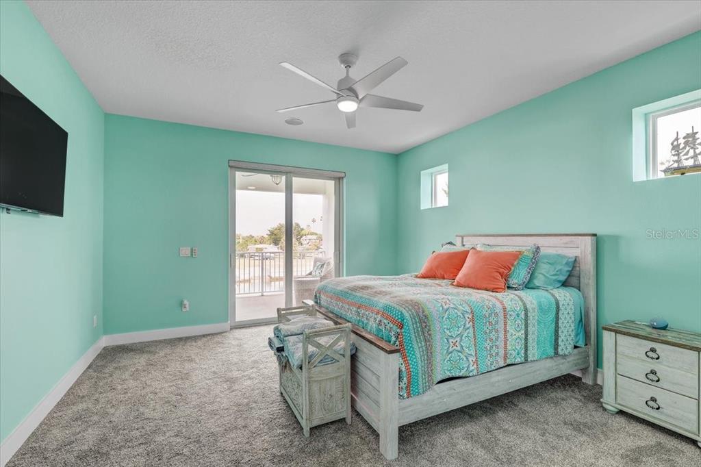 A bedroom with mint green walls, a bed, a ceiling fan, and a sliding glass door — 4389 5TH ISLE DRIVE, HERNANDO BEACH, FL