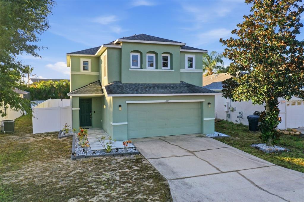 A two-story green house with a two-car garage and a paved walkway — 429 RONA LANE, DAVENPORT, FL