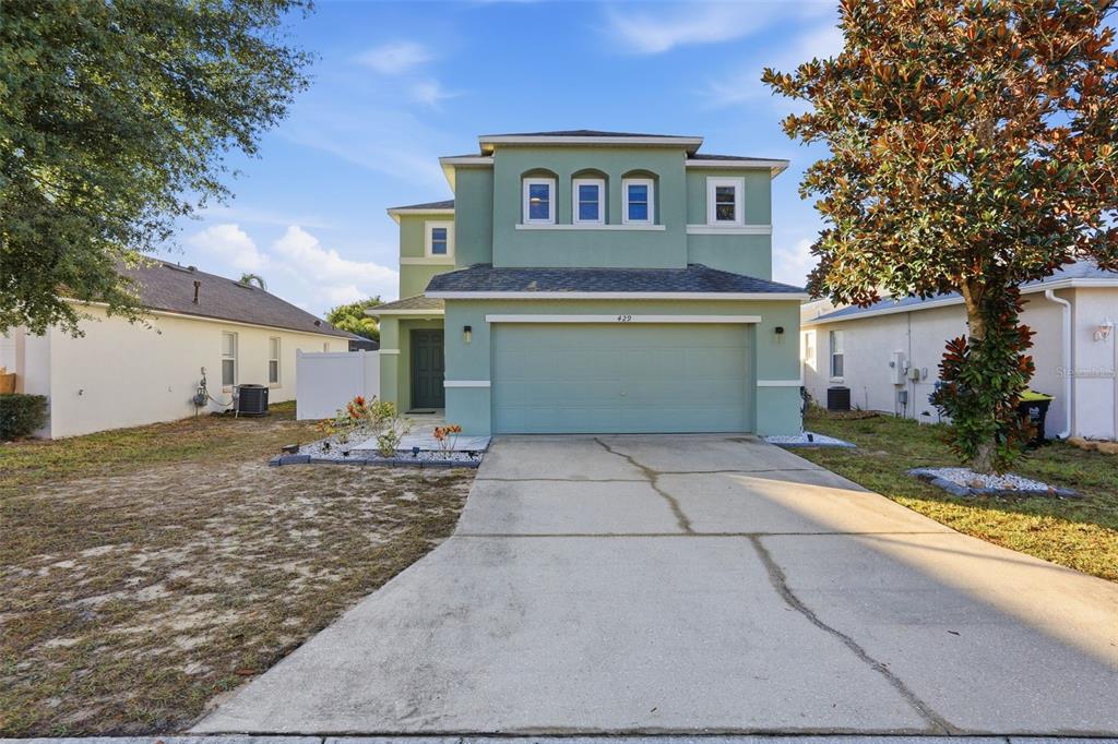 A two-story green house with a two-car garage and a concrete driveway — 429 RONA LANE, DAVENPORT, FL