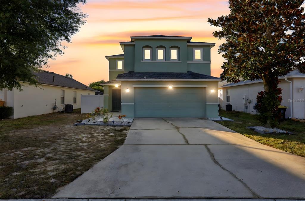 A two-story house with a green exterior, a two-car garage, and a concrete driveway — 429 RONA LANE, DAVENPORT, FL