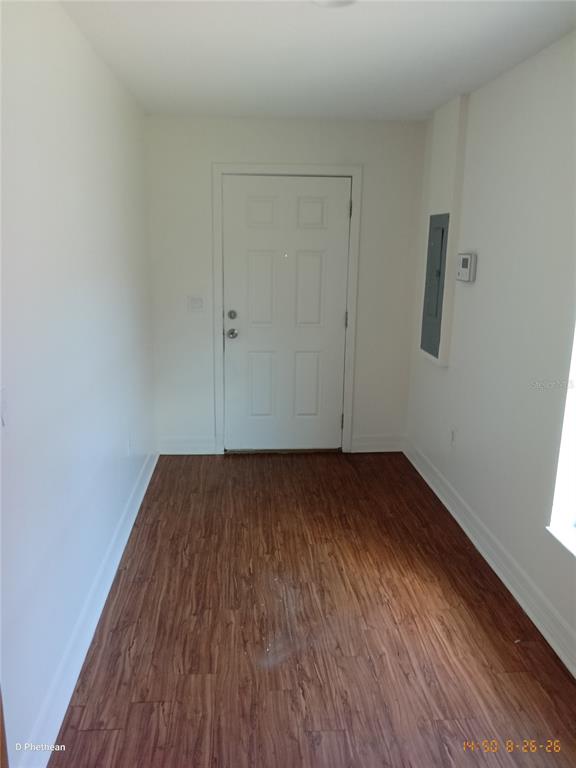 An empty room with white walls, wood-look flooring, a white door, and an electrical panel — 3814 N GARRISON STREET UNIT B, TAMPA, FL