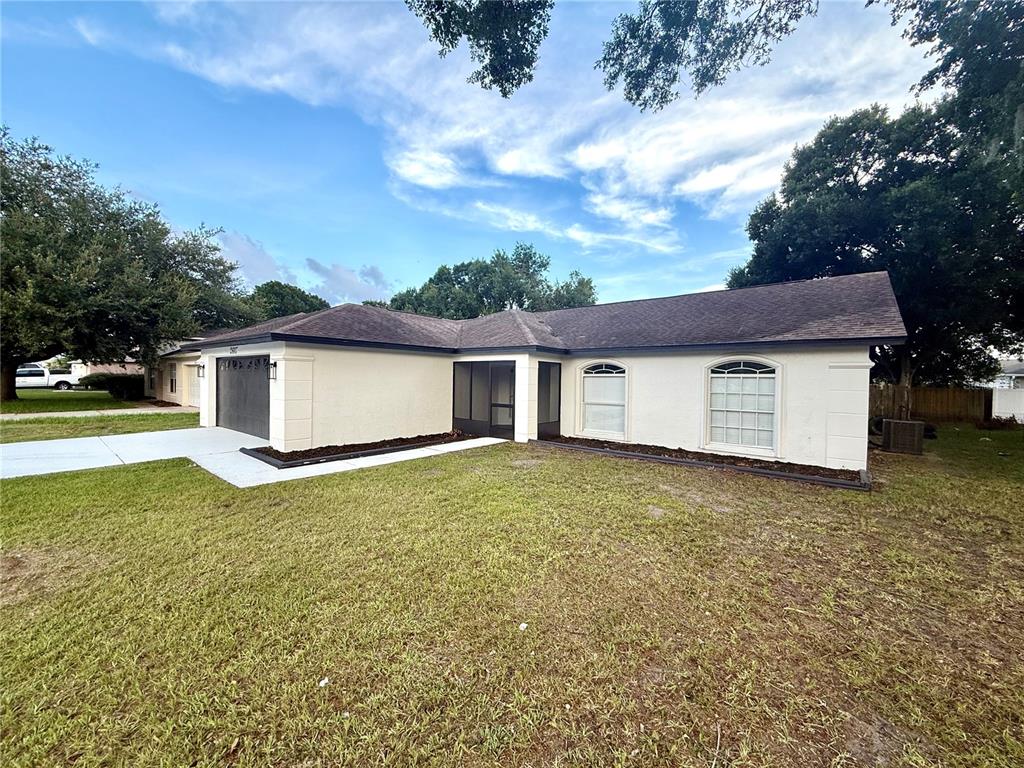 A single-story house with a dark garage door, white exterior walls, and a paved driveway — 2617 SUNDANCE CIRCLE, MULBERRY, FL