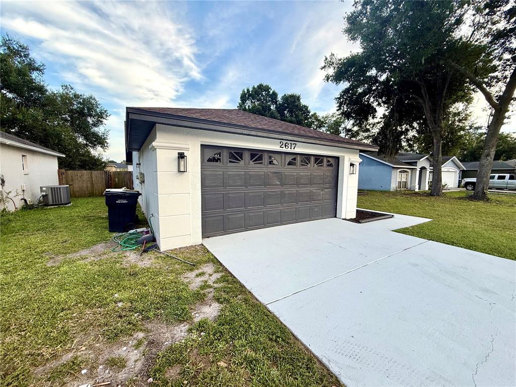 A view from a kitchen into an open living area with wood-look flooring and sliding doors — 2617 SUNDANCE CIRCLE, MULBERRY, FL
