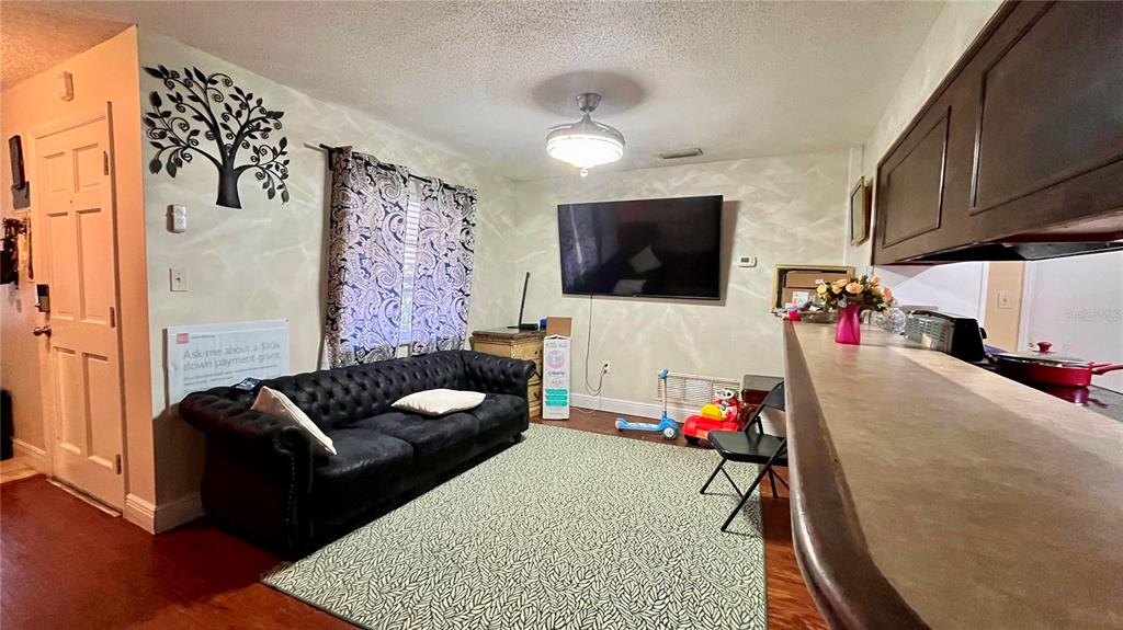 A living room features a black tufted sofa, a wall-mounted television, and a breakfast bar — 2615 CECILE STREET, KISSIMMEE, FL
