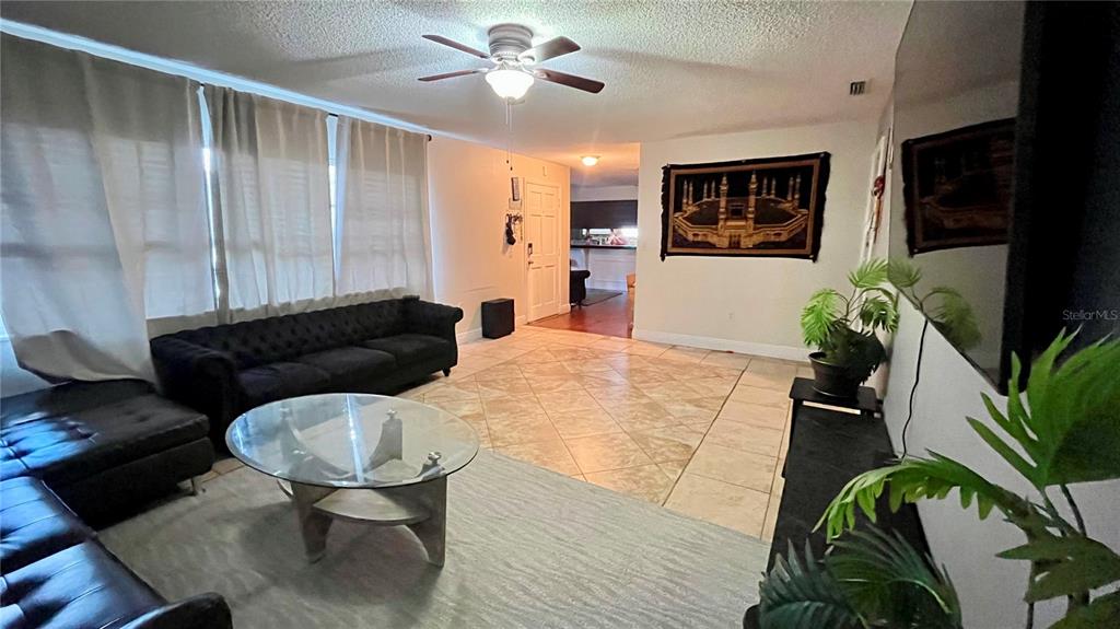 A living room features a black sofa, glass coffee table, tile flooring, and a ceiling fan — 2615 CECILE STREET, KISSIMMEE, FL
