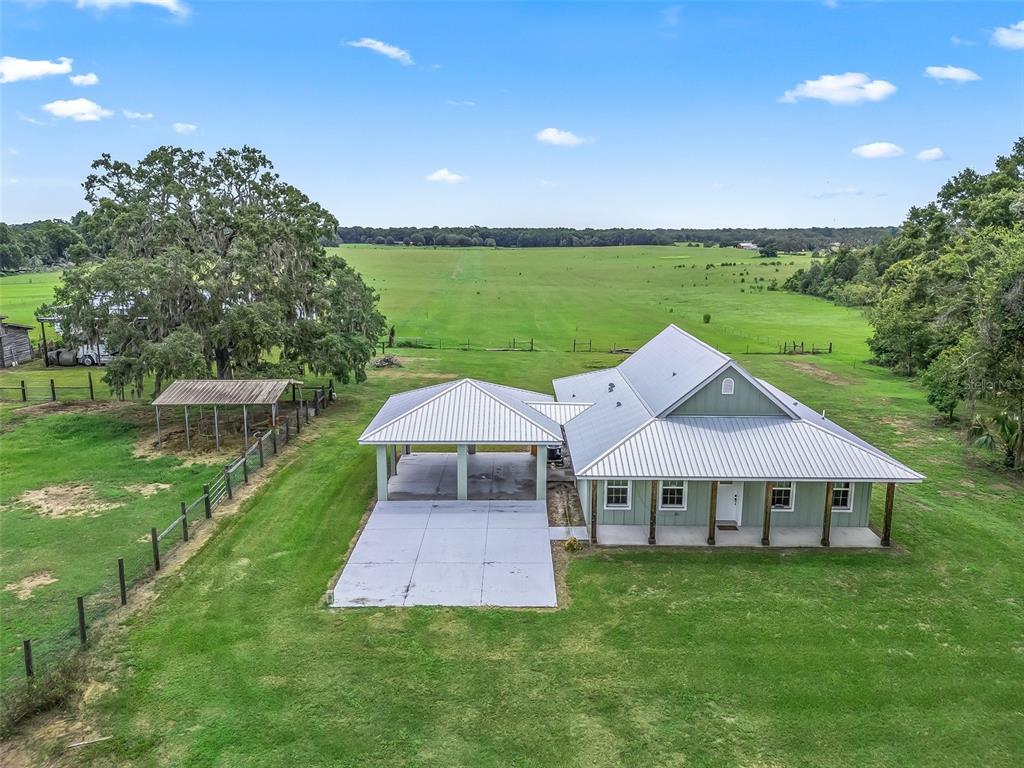 An aerial view shows a house with a metal roof, a carport, and a large pasture — 8567 CR 635, BUSHNELL, FL