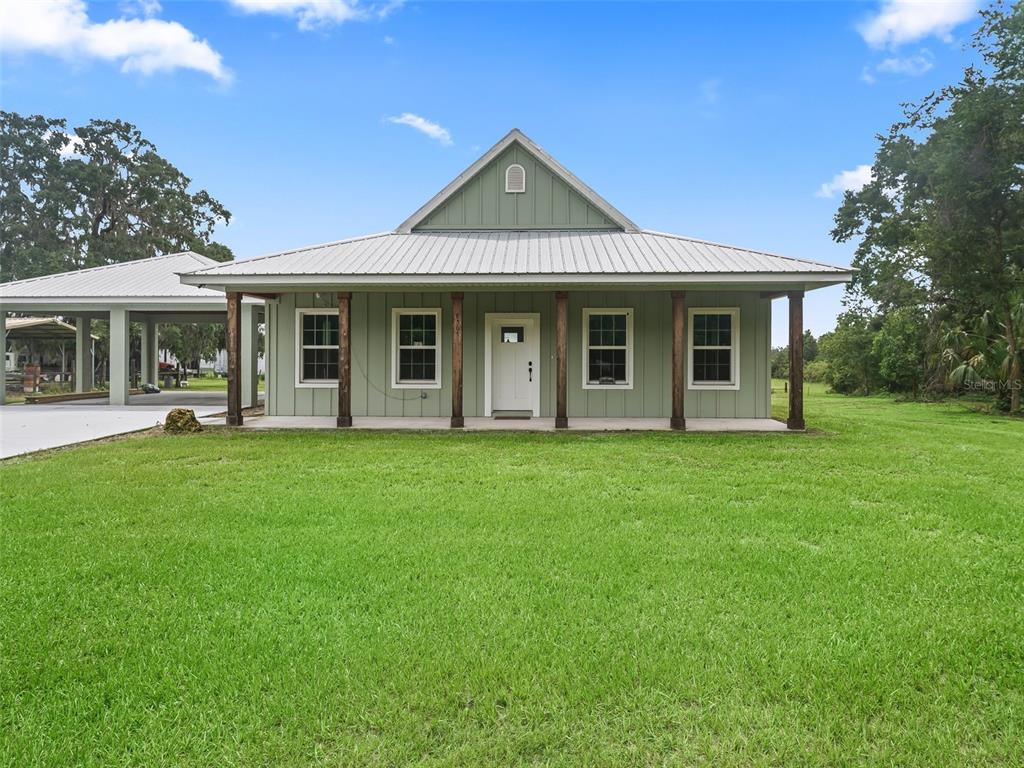 A light green house with a metal roof and a front porch sits on grass — 8567 CR 635, BUSHNELL, FL