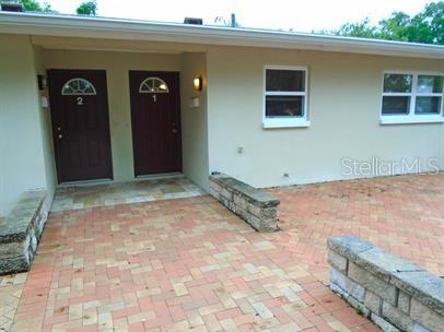 A beige building exterior features two dark brown doors labeled 1 and 2 with brick pavers — 7100 DARTMOUTH AVENUE N UNIT 3, ST PETERSBURG, FL