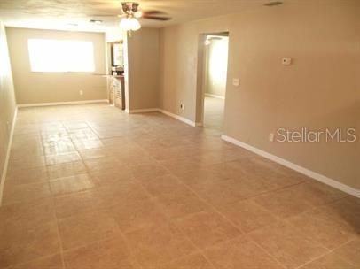A spacious room with light-colored tile flooring, beige walls, and a ceiling fan — 7100 DARTMOUTH AVENUE N UNIT 3, ST PETERSBURG, FL
