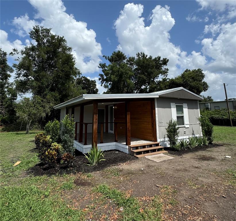 A covered porch features a herringbone-patterned floor, wood-paneled wall, and recessed ceiling lighting — 1119 N PARSONS AVENUE, SEFFNER, FL