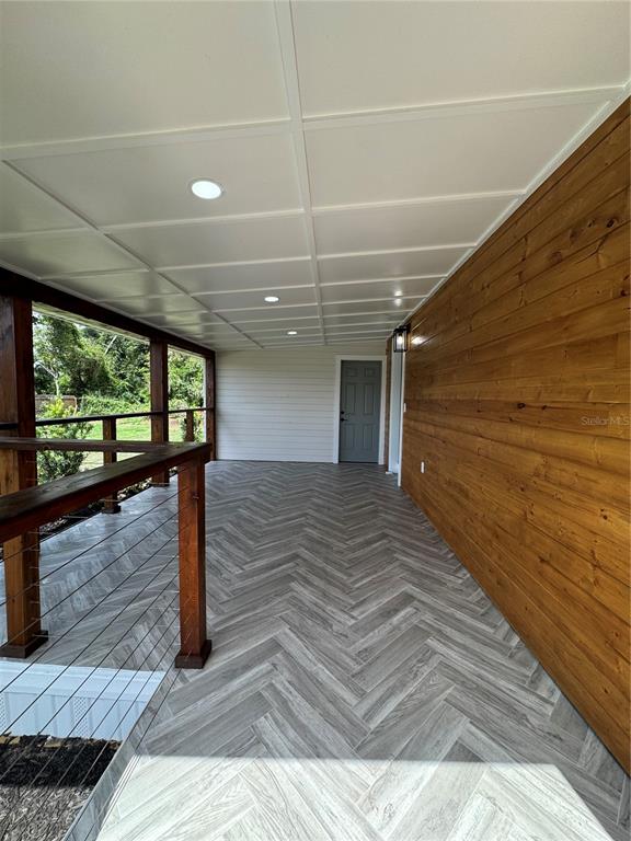 A covered porch features a herringbone-patterned floor, wood-stained posts, and horizontal wood siding — 1119 N PARSONS AVENUE, SEFFNER, FL