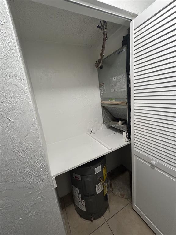 A utility closet contains a water heater beneath a shelf supporting an HVAC air handler — 1216 KENNEDY ROAD UNIT 16, DAYTONA BEACH, FL