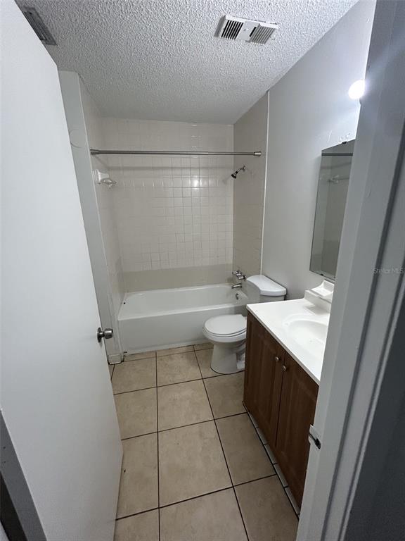 A bathroom featuring a tiled floor, a white bathtub with a shower, and a wooden vanity — 1216 KENNEDY ROAD UNIT 16, DAYTONA BEACH, FL