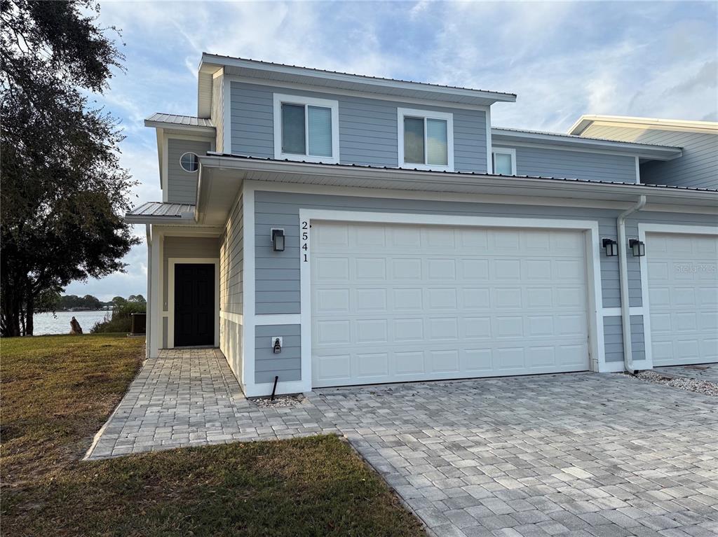 A two-story light blue duplex with a white metal roof and a paver driveway — 2541 PINE PLACE, WINTER HAVEN, FL