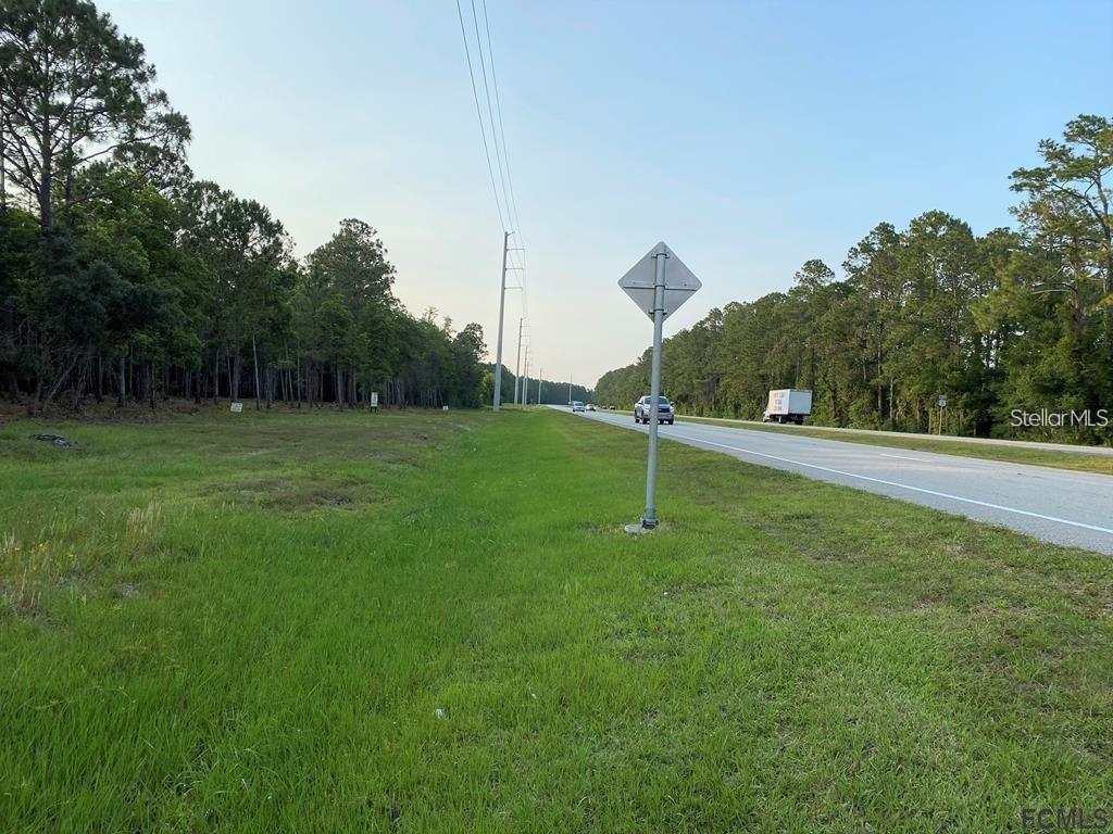A grassy roadside lot borders a paved highway with a utility pole and road sign — 53XX US HWY 1 N, BUNNELL, FL
