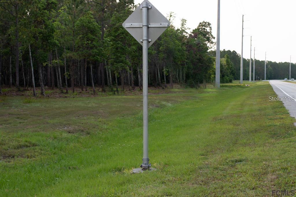 A metal sign post stands in a grassy field next to a road and trees — 53XX US HWY 1 N, BUNNELL, FL