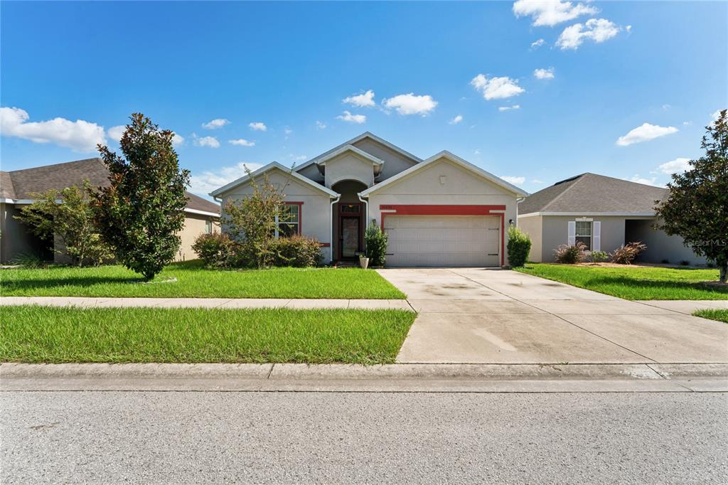 A single-story house with a beige stucco exterior, a two-car garage, and a front lawn — 30896 SATINLEAF RUN, BROOKSVILLE, FL