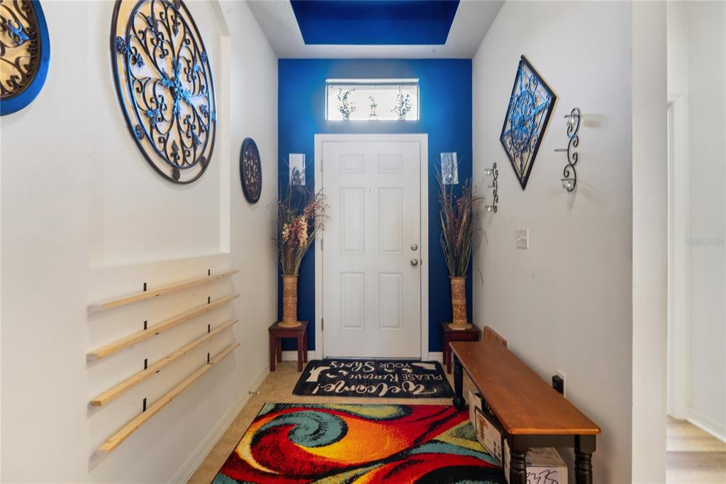 A front entryway features a red-trimmed door, a black bench, and a concrete porch — 30896 SATINLEAF RUN, BROOKSVILLE, FL