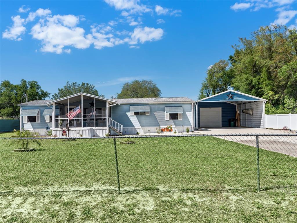 A light blue manufactured home with a screened porch and an attached metal carport — 9975 SE 166TH STREET, SUMMERFIELD, FL