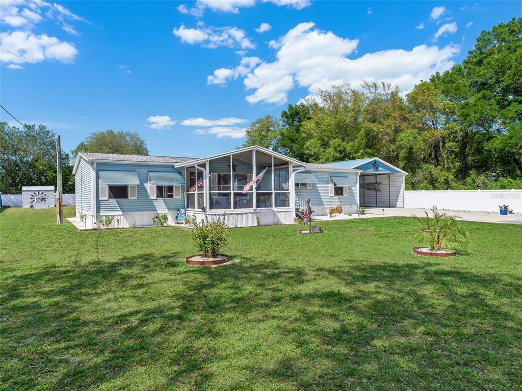 A light blue manufactured home with a screened-in porch and an attached metal carport — 9975 SE 166TH STREET, SUMMERFIELD, FL