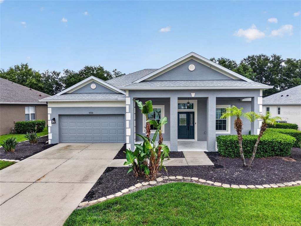 A gray single-story house with a two-car garage, covered entryway, and landscaped front yard — 5006 RISHLEY RUN WAY, MOUNT DORA, FL