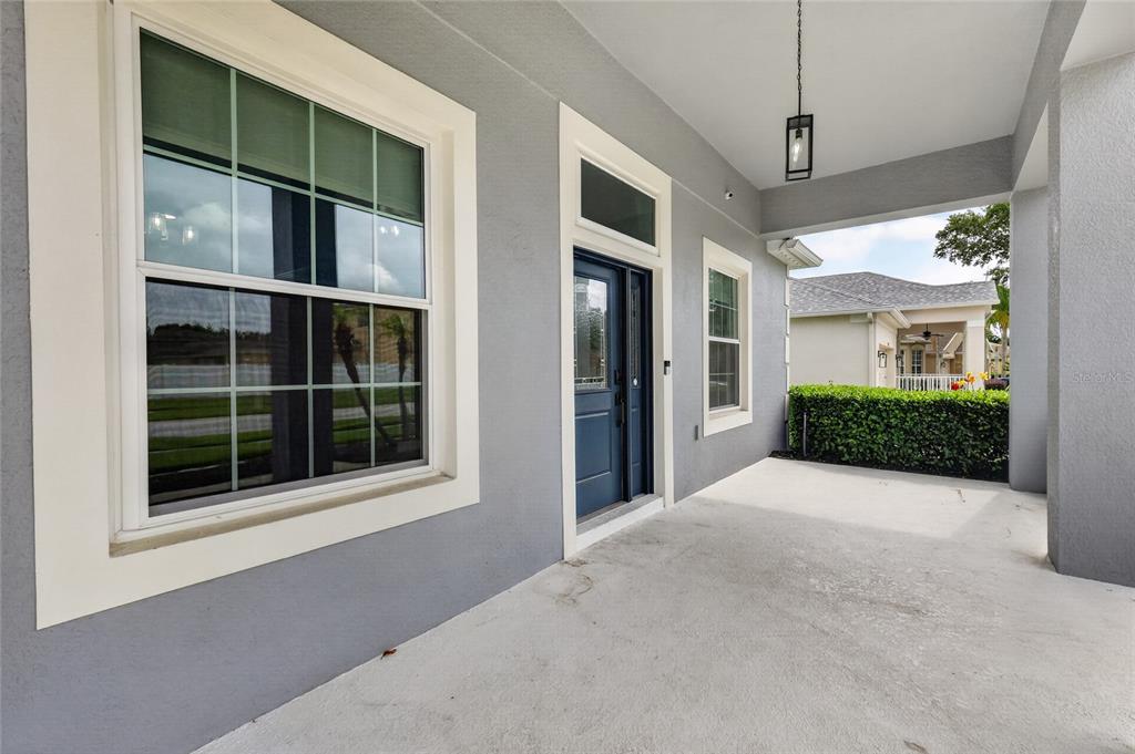 A covered porch with a blue front door, a large window, and a hanging light — 5006 RISHLEY RUN WAY, MOUNT DORA, FL