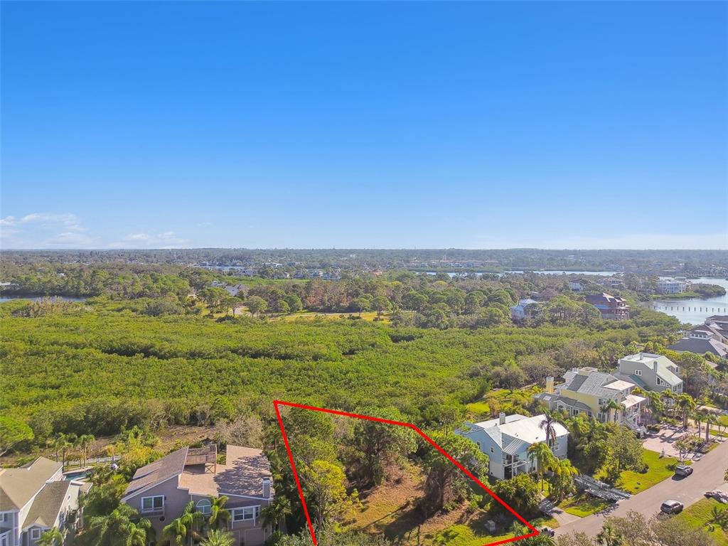 An aerial view shows a vacant, tree-covered residential lot outlined in red between two houses — POINT SEASIDE DRIVE, CRYSTAL BEACH, FL