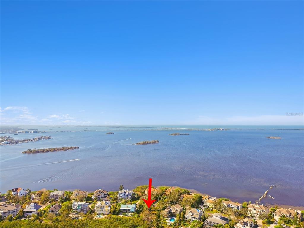 An aerial view shows a waterfront residential neighborhood with a red arrow pointing toward a lot — POINT SEASIDE DRIVE, CRYSTAL BEACH, FL