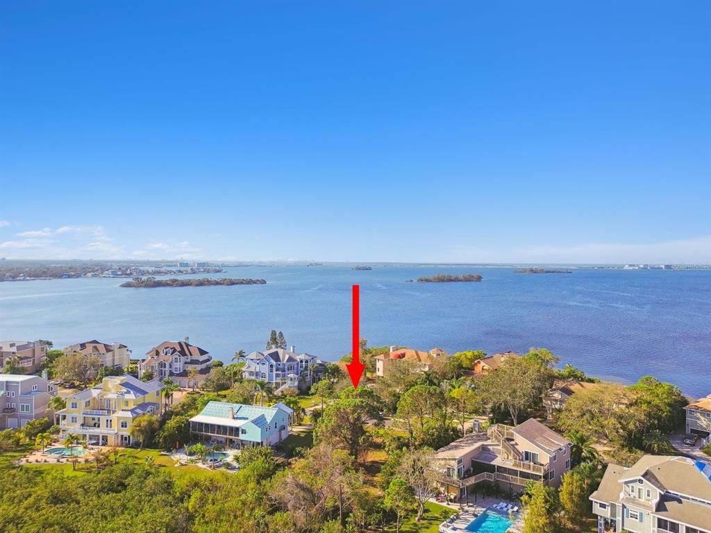 An aerial view shows a waterfront lot with trees surrounded by residential houses — POINT SEASIDE DRIVE, CRYSTAL BEACH, FL