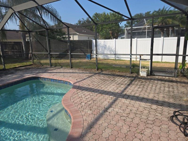 A swimming pool with a brick paver deck is enclosed by a screened lanai — 6717 GUILFORD CREST DRIVE, APOLLO BEACH, FL