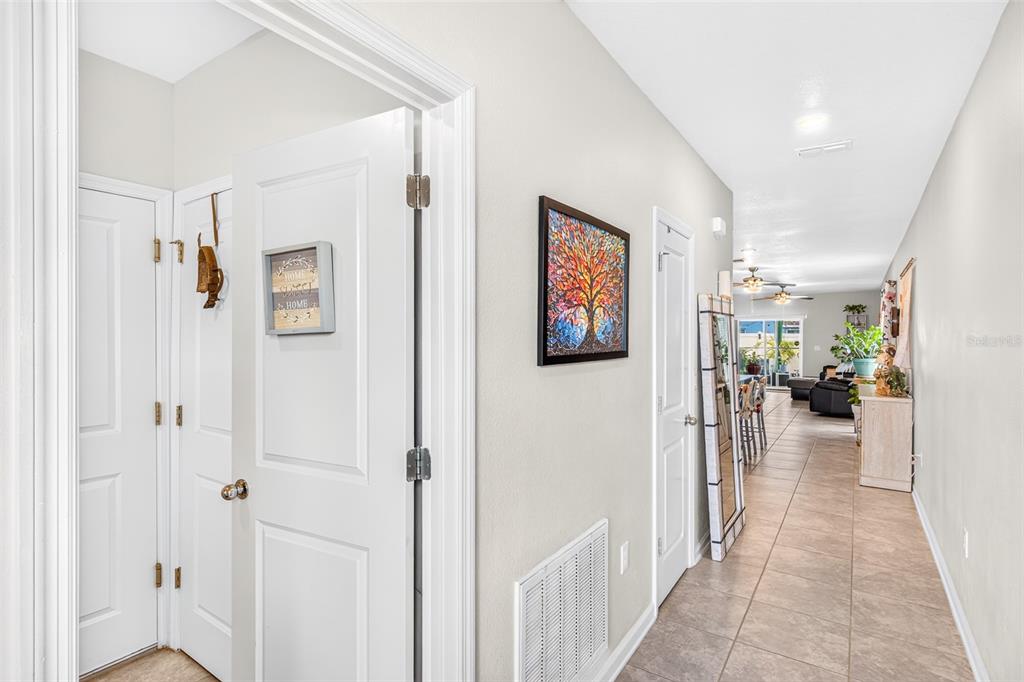 A hallway with tile flooring leads from a doorway toward an open-concept living area — 617 TROTTERS DRIVE, EAGLE LAKE, FL