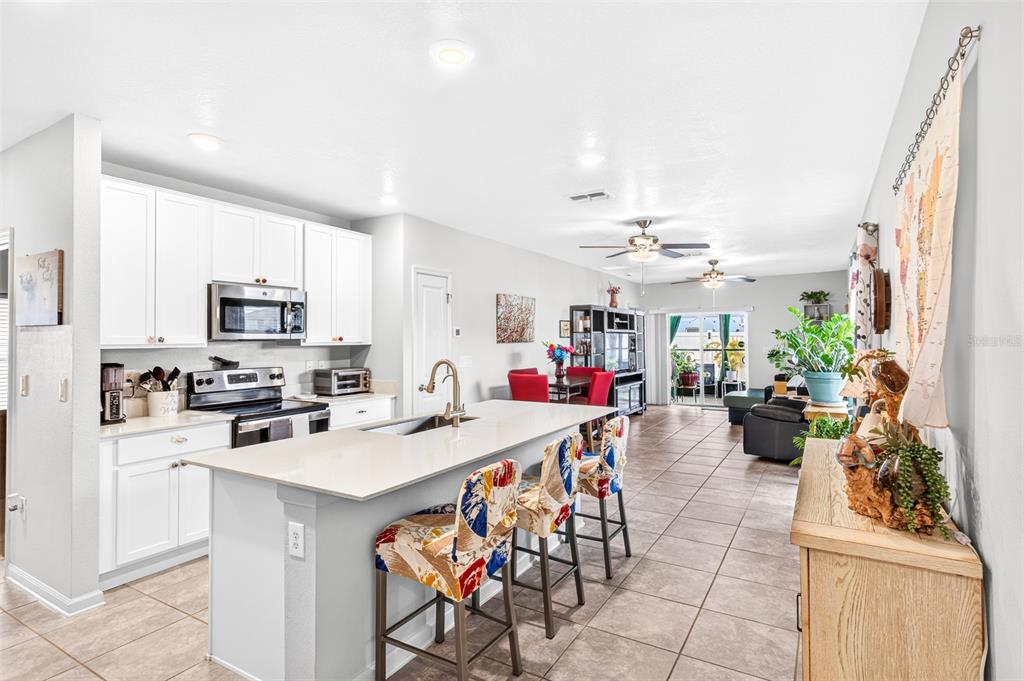 A kitchen with white cabinets and a center island opens into a dining and living area — 617 TROTTERS DRIVE, EAGLE LAKE, FL