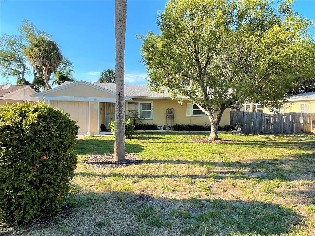 A single-story house with a tan exterior, a front-facing garage, and a large shade tree — 9 JEFF ROAD, LARGO, FL
