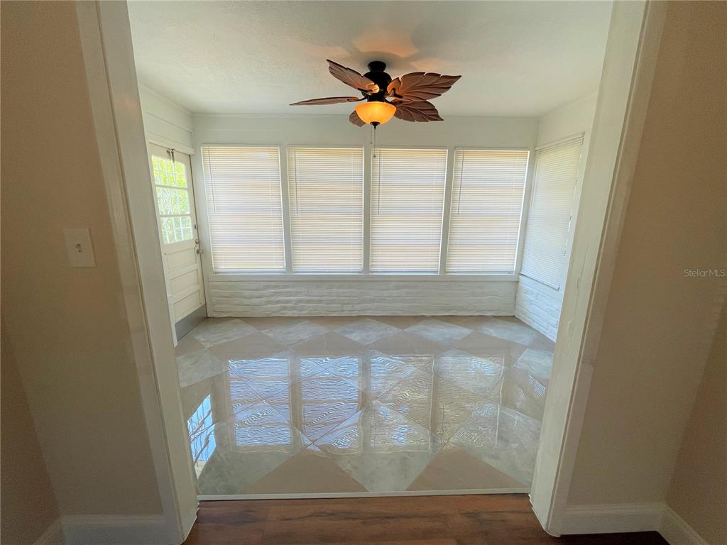 A sunroom features a leaf-shaped ceiling fan, white brick walls, and diamond-patterned tile flooring — 9 JEFF ROAD, LARGO, FL