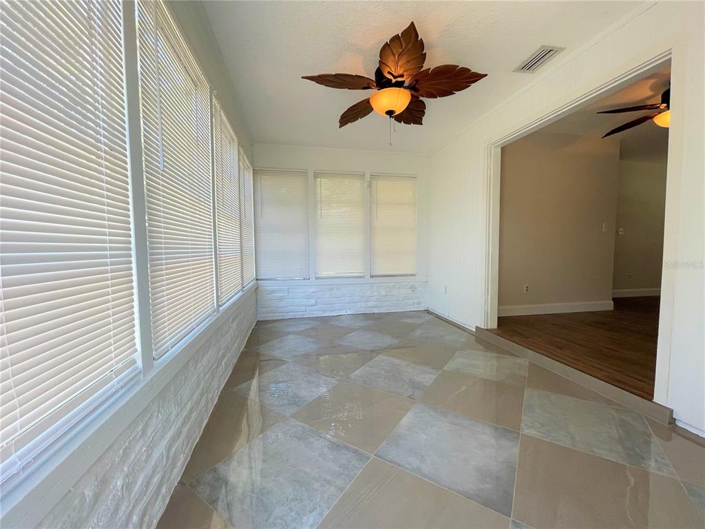A sunroom features a leaf-shaped ceiling fan, tiled floor, and white brick wall accents — 9 JEFF ROAD, LARGO, FL