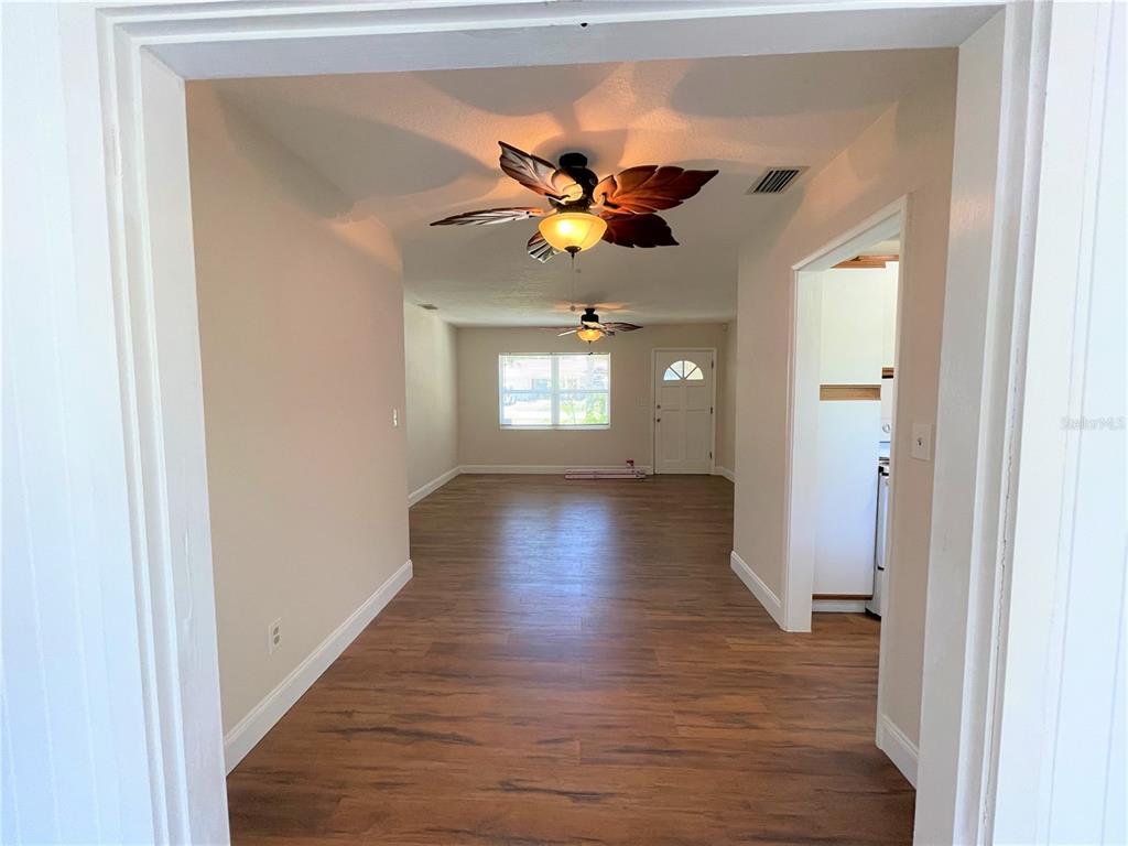 A view through a doorway into a living room with wood-look flooring and ceiling fans — 9 JEFF ROAD, LARGO, FL