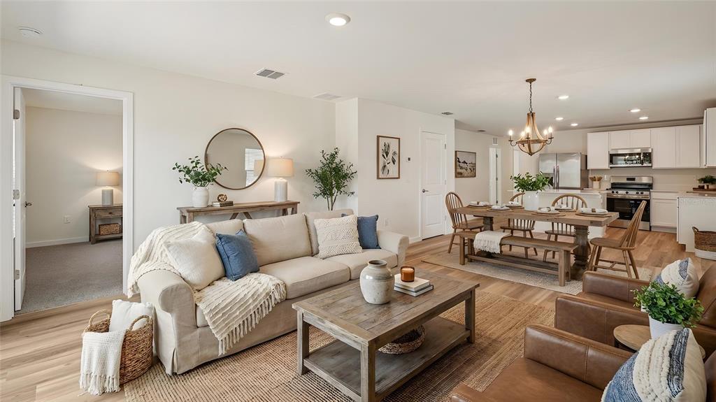 An open-concept living room and dining area feature light wood floors and neutral decor — 1029 COMMONS WAY, PORT ORANGE, FL