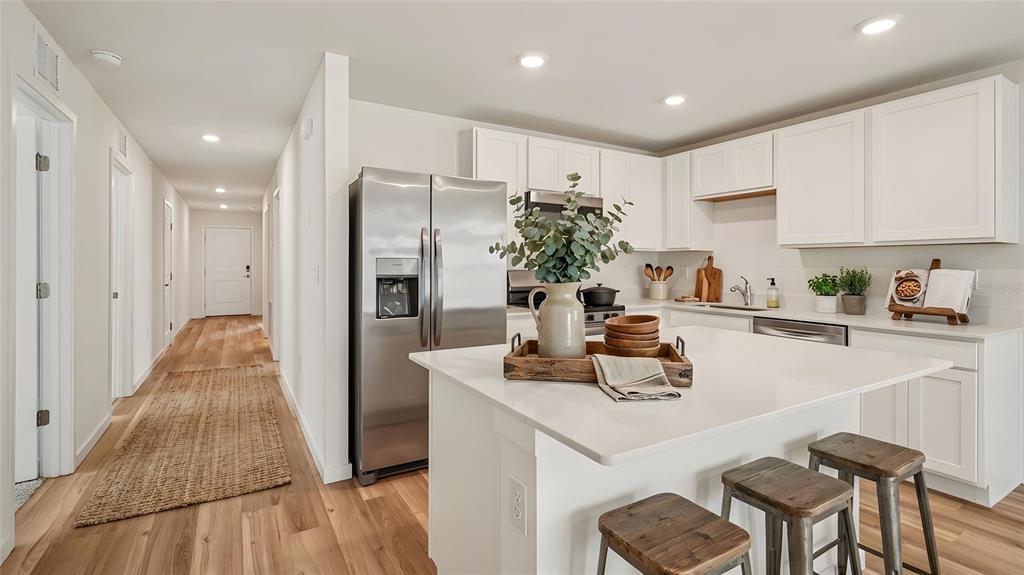 A modern kitchen features white cabinetry, a stainless steel refrigerator, and a central island — 1029 COMMONS WAY, PORT ORANGE, FL