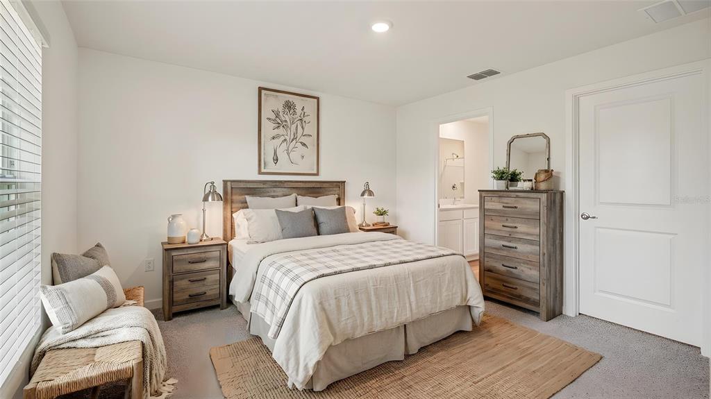 A bedroom features a bed with a plaid comforter, wooden furniture, and a small bench — 1029 COMMONS WAY, PORT ORANGE, FL