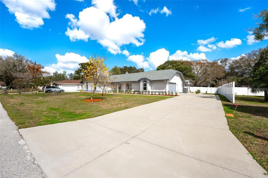 A single-story house with a gray roof and a large concrete driveway under a blue sky — 5521 OAK STREET, MOUNT DORA, FL