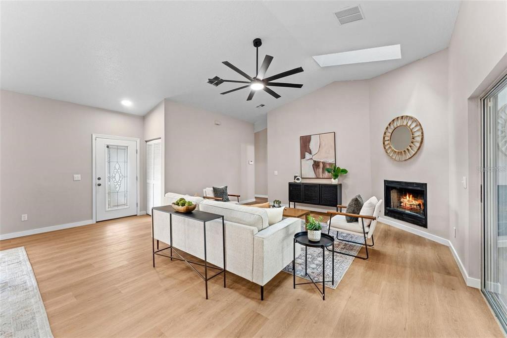A living room features light wood flooring, a fireplace, a ceiling fan, and neutral walls — 5521 OAK STREET, MOUNT DORA, FL