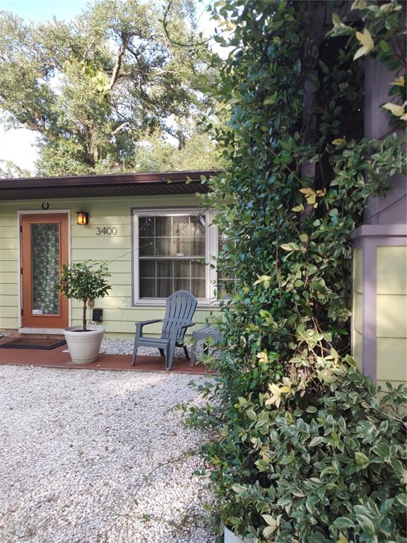 A light green house exterior features a front door, a window, and a gray chair — 3400 CLARK DRIVE, SARASOTA, FL